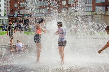 Novokuznetsk, Kemerovo Region, Russia - August 04, 2018: Happy teenagers splashing in a water of a city fountain and enjoying the cool streams of water in a hot day.のeditorial素材
