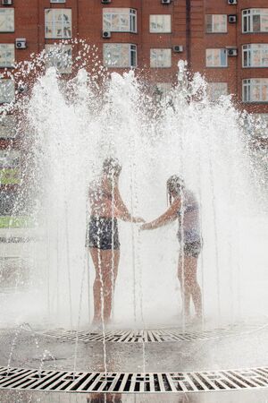 Novokuznetsk, Kemerovo Region, Russia - August 04, 2018: Happy teenagers splashing in a water of a city fountain and enjoying the cool streams of water in a hot day.のeditorial素材