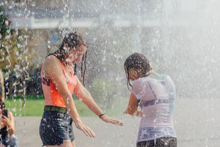 Novokuznetsk, Kemerovo Region, Russia - August 04, 2018: Happy teenagers splashing in a water of a city fountain and enjoying the cool streams of water in a hot day.のeditorial素材