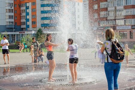 Novokuznetsk, Kemerovo Region, Russia - August 04, 2018: Happy teenagers splashing in a water of a city fountain and enjoying the cool streams of water in a hot day.のeditorial素材