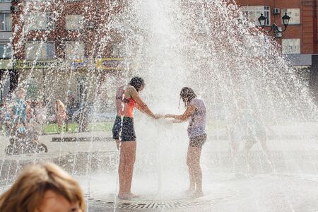 Novokuznetsk, Kemerovo Region, Russia - August 04, 2018: Happy teenagers splashing in a water of a city fountain and enjoying the cool streams of water in a hot day.のeditorial素材