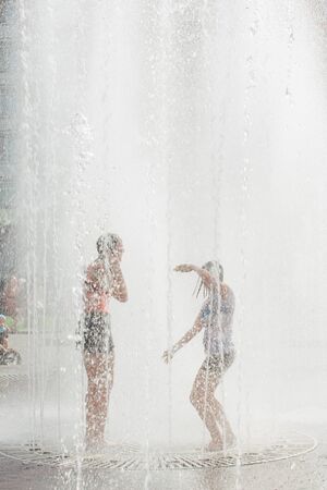 Novokuznetsk, Kemerovo Region, Russia - August 04, 2018: Happy teenagers splashing in a water of a city fountain and enjoying the cool streams of water in a hot day.のeditorial素材