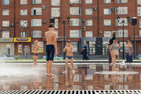 Novokuznetsk, Kemerovo Region, Russia - August 04, 2018: Happy children splashing in a water of a city fountain and enjoying the cool streams of water in a hot day.のeditorial素材