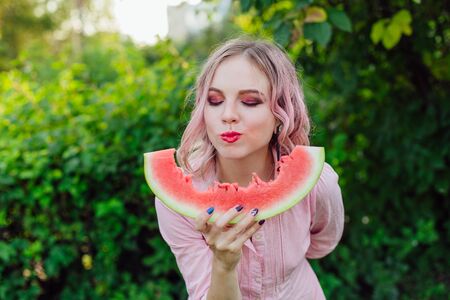 Beautiful young woman with pink hair enjoying sweet juicy watermelonの写真素材