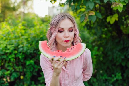 Beautiful young woman with pink hair enjoying sweet juicy watermelonの写真素材