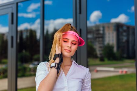 Portrait of an emotional beautiful young girl in a pink cap visor and protective glovesの写真素材