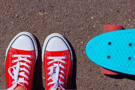 Close up of feet of a girl in red sneakers and blue penny skate board with pink wheels on the background. Urban scene, city life. Sport, fitness lifestyle.の写真素材