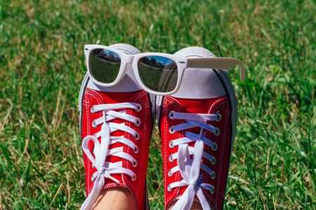 Red sneakers shoes and mirror sunglasses on woman's feet. Sneakers shoes Couple. Copy space.の写真素材