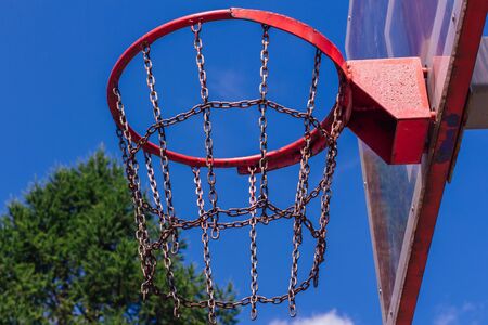 Outdoor basketball ring in front of green trees background. Sport concept.の写真素材