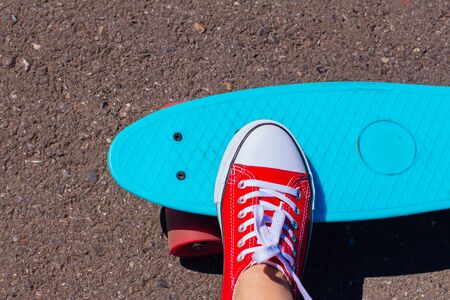 Close up of feet of a girl in red sneakers and blue penny skate board with pink wheels on the background. Urban scene, city life. Sport, fitness lifestyle.の写真素材
