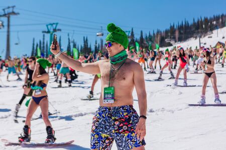 Sheregesh, Kemerovo region, Russia - April 13, 2019: Grelka Fest is a sports and entertainment activity for ski and snowboard riders in bikini. Crowd of people riding snowboard and mountain skiのeditorial素材