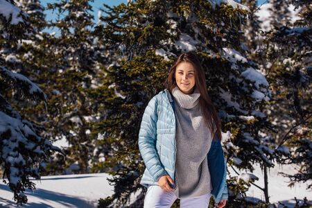 Portrait of a young beautiful brunette woman with blue eyes and freckles on face in winter snowy...