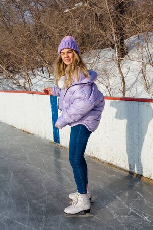 Lovely young woman riding ice skates on the ice rink. Girl skating on ice in a winter frosty day