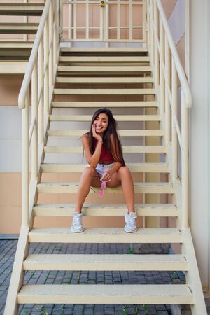 Street fashion summer portrait of a women on stairs outdoors. Full-length portrait young beautiful model in shorts posing on the stairs.の写真素材