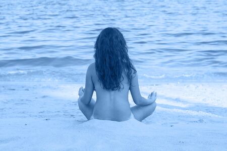Woman meditating on beach in lotus position. Color of the year 2020 Classic Blueの写真素材
