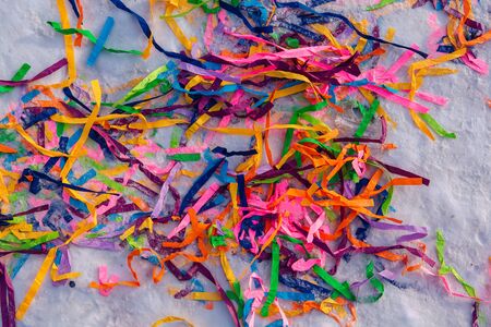 Bright colorful paper ribbons in the snow. Bright background with color paper party ribbons