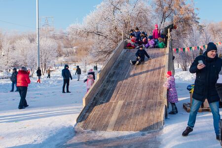 Novokuznetsk, Russia- January 07, 2019: Russian winter entertainment: children having fun tobogganing from wooden toboggan in a frosty winter dayのeditorial素材