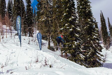 Sheregesh, Kemerovo region, Russia - April 08, 2019: Jaws Slash Camp is a snowboard and mountain ski competition where riders doing extreme tricks. Snowboard rider jumping and doing a trickのeditorial素材