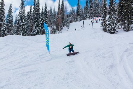 Sheregesh, Kemerovo region, Russia - April 08, 2019: Jaws Slash Camp is a snowboard and mountain ski competition where riders doing extreme tricks. Snowboard rider jumping and doing a trickのeditorial素材