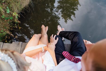 Front view of wedding couple's feet sitting on the wooden bridge. Top view.の写真素材
