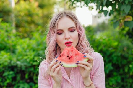 Beautiful young woman with pink hair enjoying sweet juicy watermelonの写真素材