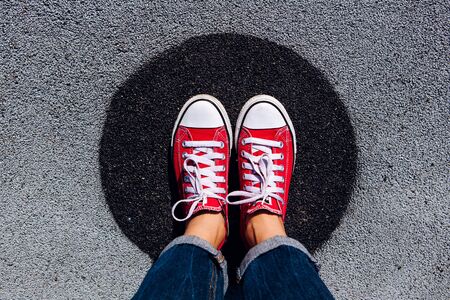 Red sneakers shoes on woman's feet on the asphalt with black circle. Sneakers shoes Couple. Copy space.の写真素材
