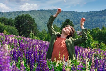 Tall handsome man standing and dancing on lupine flowers fieldの写真素材
