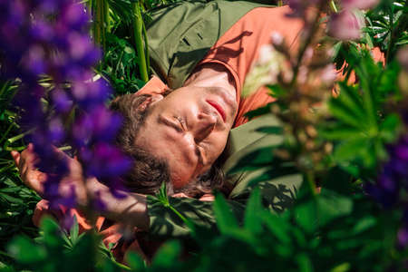 Tall handsome lying among the lupines flowers