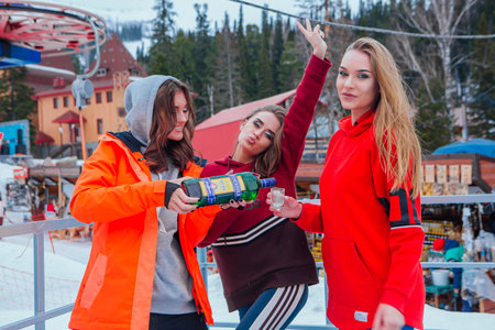 Sheregesh, Russia-April 14, 2018: Three beautiful women drinking Becherovka outdoors at ski resort....
