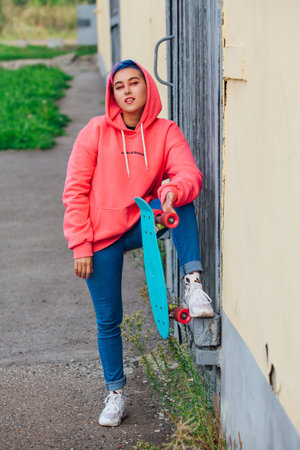 Stylish young woman holding skateboard in hand. Youth concept.の写真素材