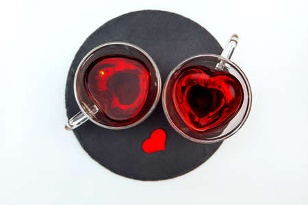 Two transparent heart-shaped cups with tea on the white background. Top view.の写真素材