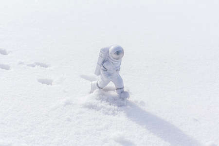 Statuette of an astronaut confidently explores alien planet's surface. Cold planet covered with...