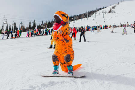 Sheregesh, Kemerovo region, Russia - April 03, 2021: Grelka Fest is a sports and entertainment activity for ski and snowboard riders. People in carnival costumes riding ski and snowboard.のeditorial素材