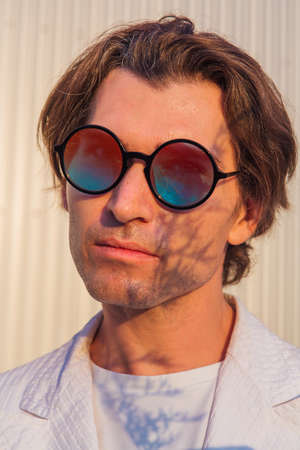 Close up portrait of a handsome man with round hippie sunglasses during sunset