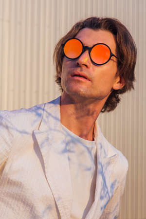Close up portrait of a handsome man with round hippie sunglasses during sunset