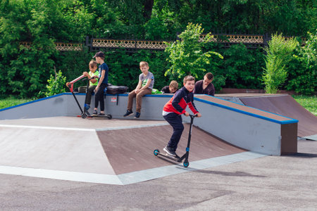 Novokuznetsk, Russia - July 19, 2021: Group of boys ride a scooter in an extreme park. Study of extreme sports on the open air.のeditorial素材