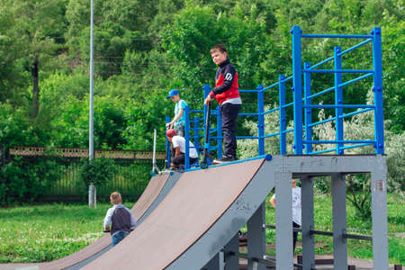 Novokuznetsk, Russia - July 19, 2021: Group of boys ride a scooter in an extreme park. Study of extreme sports on the open air.