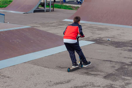Novokuznetsk, Russia - July 19, 2021: Group of boys ride a scooter in an extreme park. Study of...