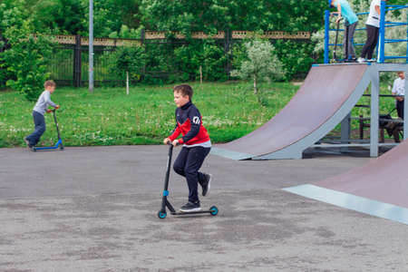 Novokuznetsk, Russia - July 19, 2021: Group of boys ride a scooter in an extreme park. Study of...