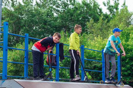 Novokuznetsk, Russia - July 19, 2021: Group of boys ride a scooter in an extreme park. Study of...