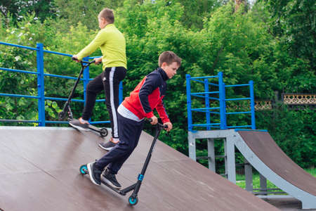 Novokuznetsk, Russia - July 19, 2021: Group of boys ride a scooter in an extreme park. Study of extreme sports on the open air.のeditorial素材
