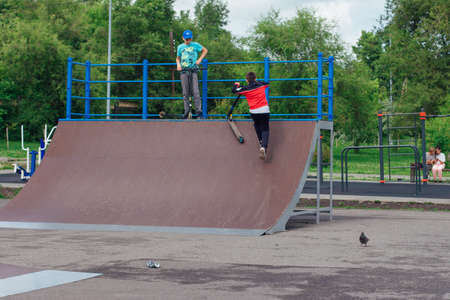 Novokuznetsk, Russia - July 19, 2021: Group of boys ride a scooter in an extreme park. Study of extreme sports on the open air.のeditorial素材