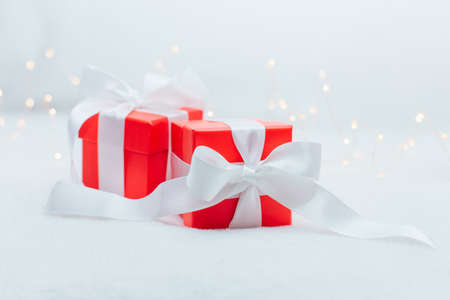 Red gift boxes bandaged whith a white ribbonon the white background with warm lights.の写真素材