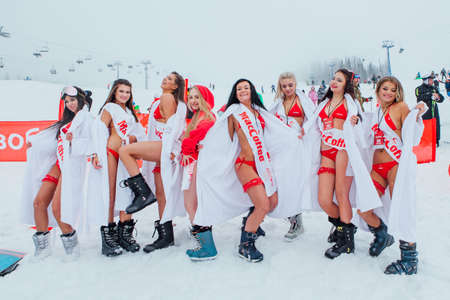 Sheregesh, Kemerovo region, Russia - April 17, 2021: Grelka Fest is a sports and entertainment activity for ski and snowboard riders. Pretty women in red bikinis and white bathrobes on the snow slope.のeditorial素材