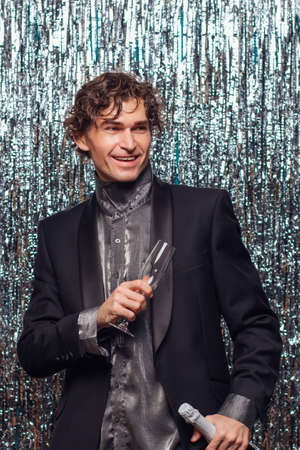 Holidays concept - happy tipsy man with bottle of champagne and wine glass at christmas or new year party on a sparkle background.の写真素材