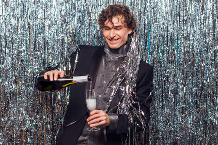 Holidays concept - happy tipsy man with bottle of champagne and wine glass at christmas or new year party on a sparkle background.の写真素材