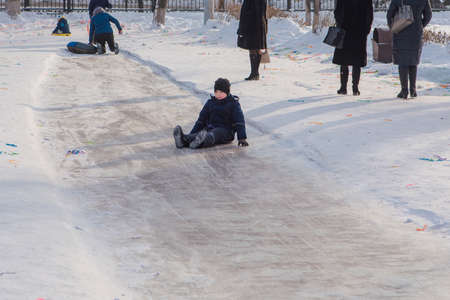 Little boy sledding on a snow slide. Winter fun.