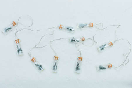 Christmas garland in a shape of little bottles with tiny christmas tree inside on a white backgroundの写真素材
