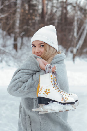 Lovely young woman with ice skates on the ice rink. Girl is going to skating on ice in a winter...