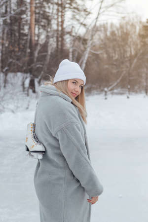 Lovely young woman with ice skates on the ice rink. Girl is going to skating on ice in a winter...
